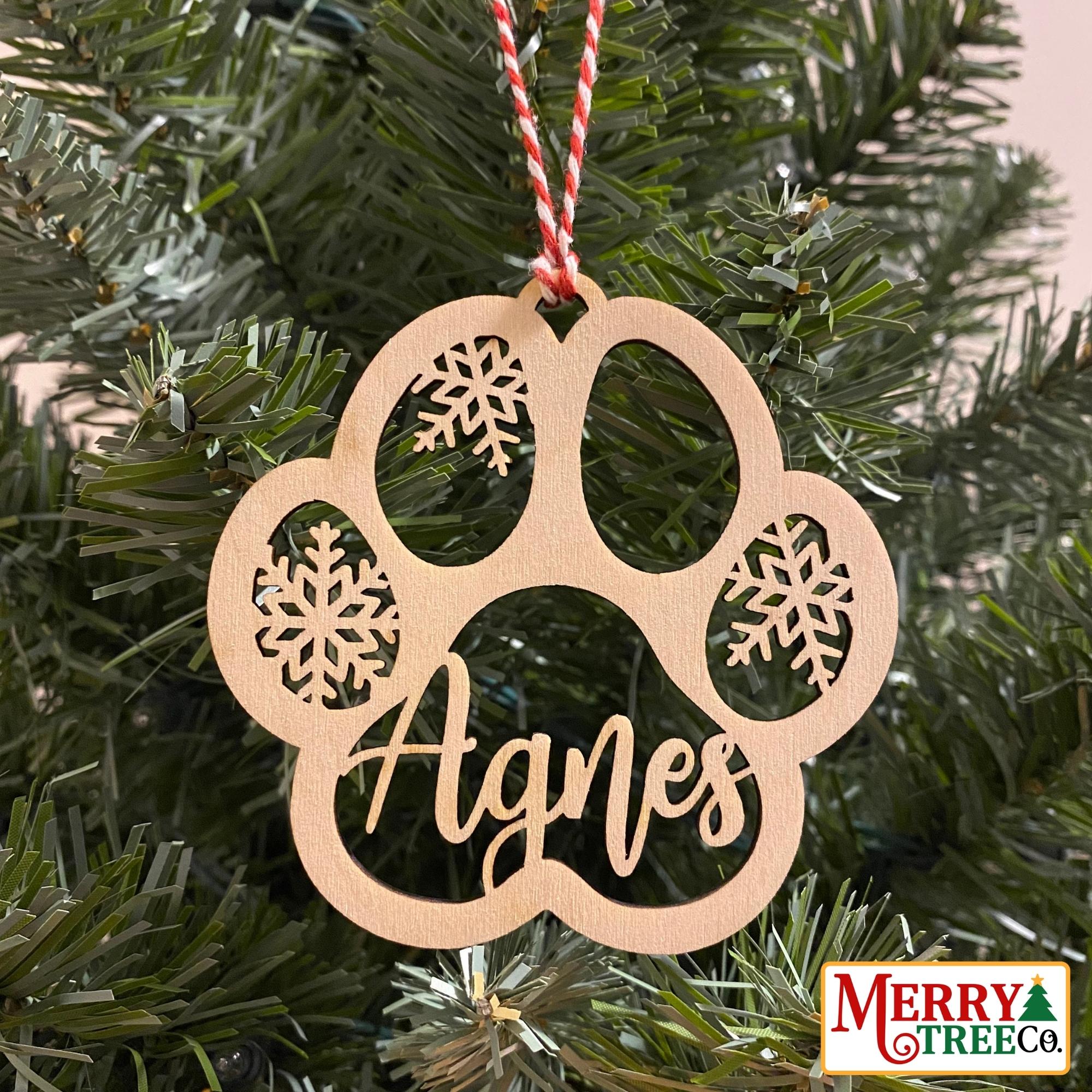 Paw print with snowflake and pets name hangs on tree.